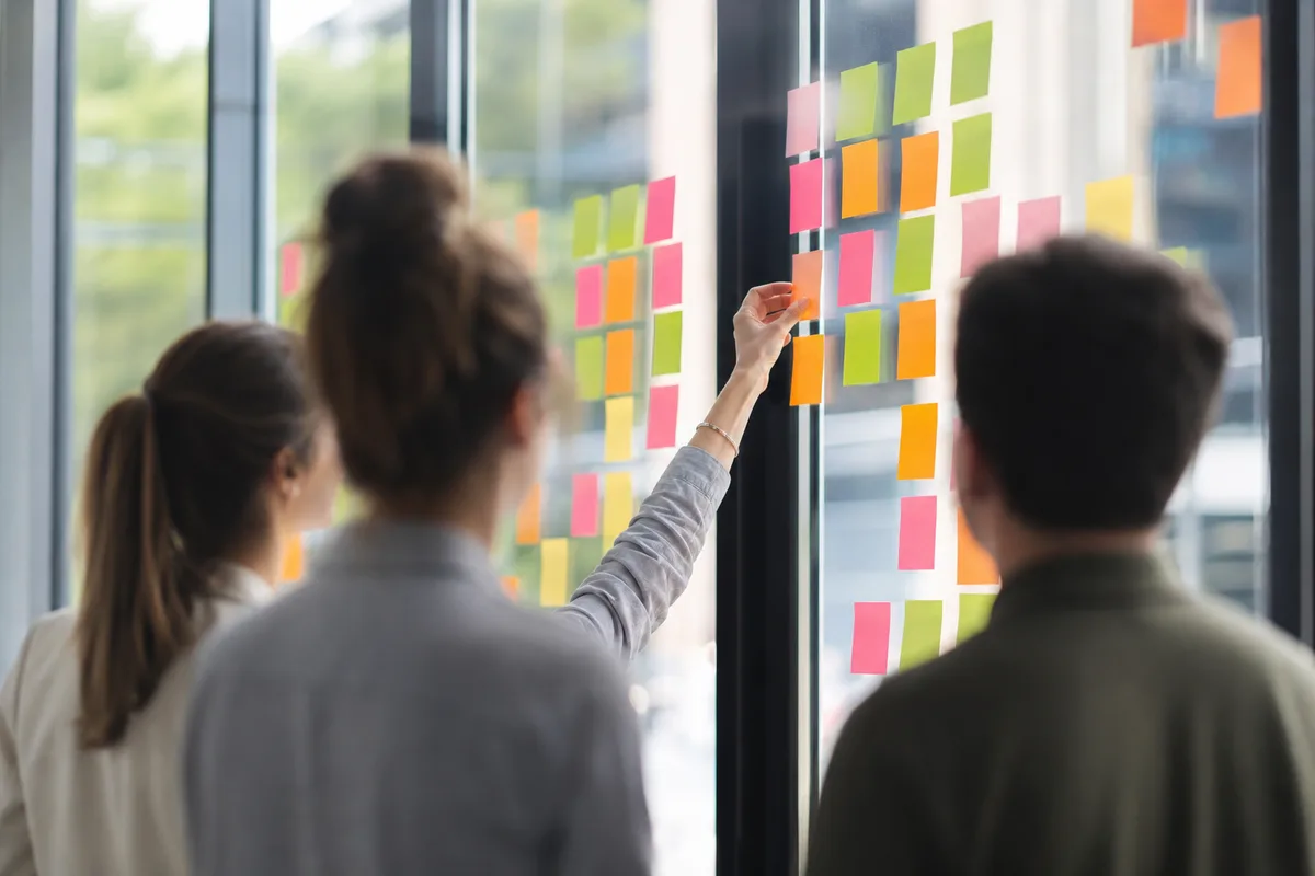 Une équipe marketing réunie autour d&rsquo;un mur couvert de notes de couleur pour planifier ses publications